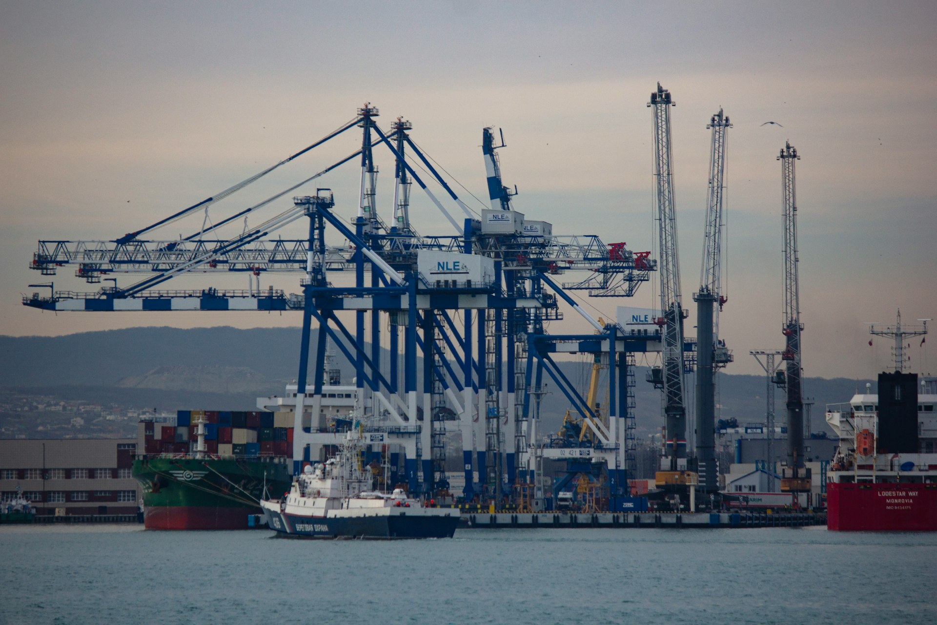 a large cargo ship in the water with a lot of cranes in the background